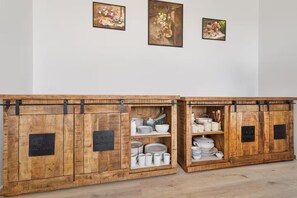 Un meuble en bois muni de crochets en métal, servant à ranger des assiettes, des bols et des tasses.
