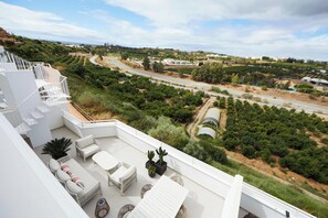 A rooftop terrace with outdoor furniture, a view of a vineyard, and a road. - Casa Hela - Large Terrace - Pool - Gym (Estepona)