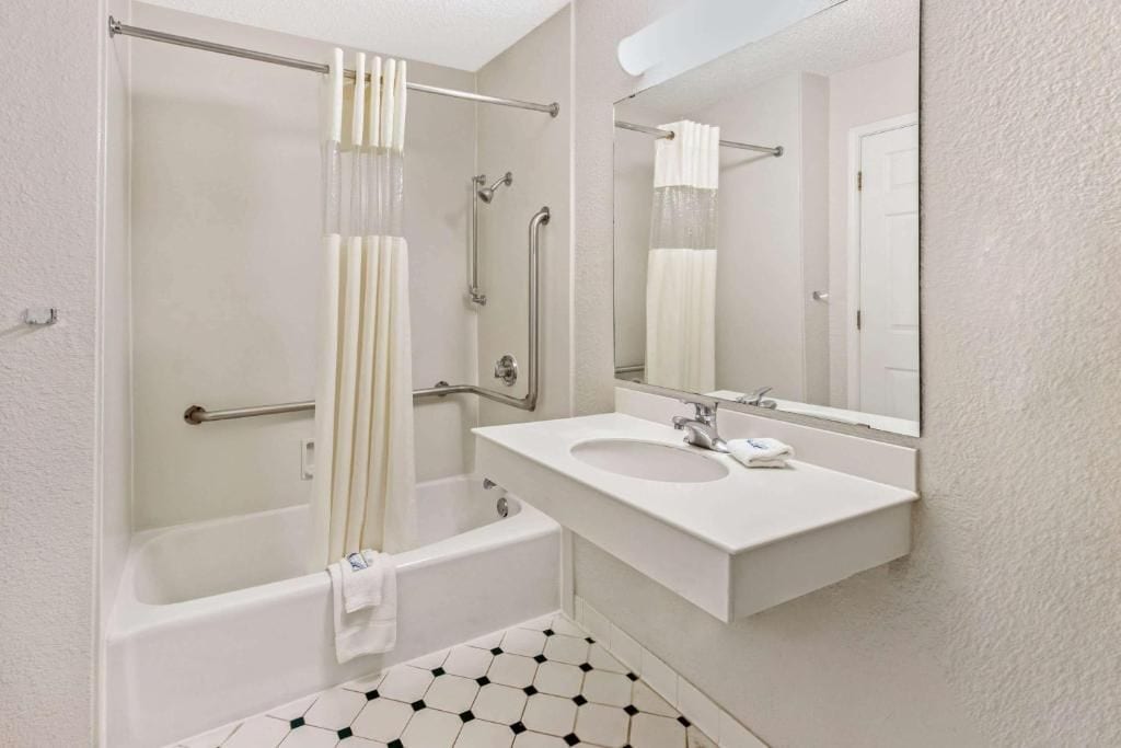Un baño con bañera, lavabo, espejo y ducha con puerta de cristal.
