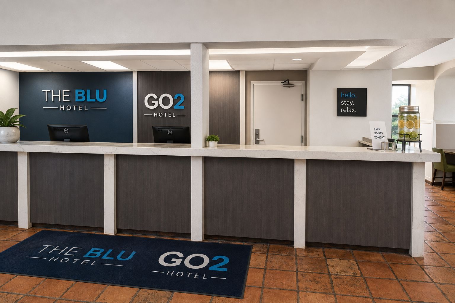 Un comptoir d'accueil d'hôtel avec une enseigne indiquant « THE BLU HOTEL » et « GO2 HOTEL ». On y trouve une plante, un ordinateur et une affiche encourageant les clients à accumuler des points.