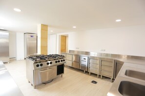 Een moderne keuken met roestvrijstalen apparatuur, waaronder een gasfornuis en een koelkast.