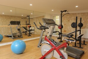 Een sportschool met trainingsapparatuur, een spiegelwand en fitnessballen.