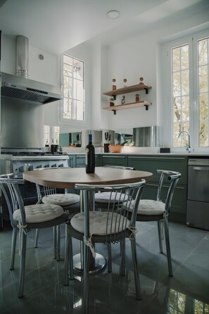 Eine moderne Küche mit einem runden Esstisch, Stühlen und einem eingebauten Backofen.