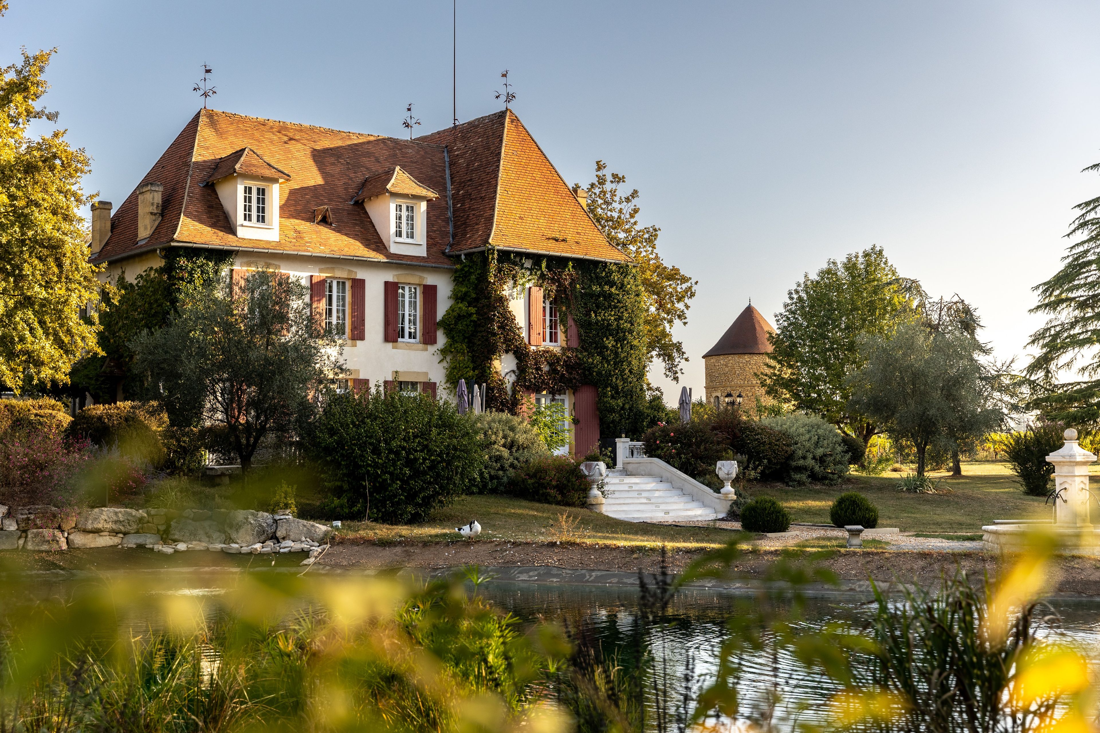 A large house with a garden and a pond.