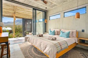 A modern bedroom with a large bed, a desk, and a view of the outdoors. - KOH Pringle Pod (Pringle Bay)