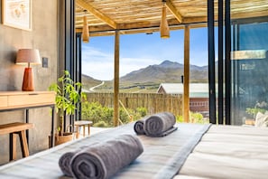 A bedroom with a large window, a wooden ceiling, and a view of mountains. - KOH Pringle Pod (Pringle Bay)