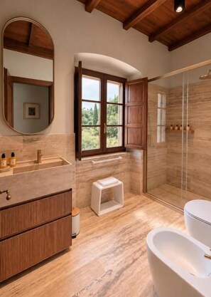 A bathroom with a wooden vanity, a large mirror, a shower with glass doors, and a window providing a view of greenery. - Villa Angelina (PROVINCIA DI AREZZO)