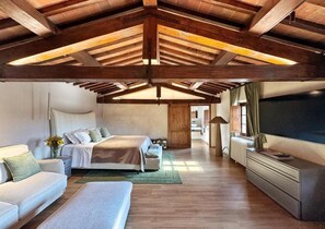 A spacious bedroom with a large bed, a sofa, and a television. - Villa Angelina (PROVINCIA DI AREZZO)