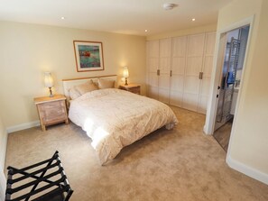 A bedroom with a bed, nightstands, a painting, a wardrobe, and a bathroom visible through an open door. - Three Chimneys (Lincoln)