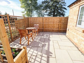A patio with a wooden fence, a brick wall, and a window. - Three Chimneys (Lincoln)