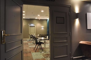 A hotel room with a door leading to a conference room with tables and chairs.