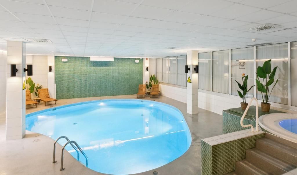 En inomhuspool med en kaklad vägg, en sittgrupp och ett bubbelbad.