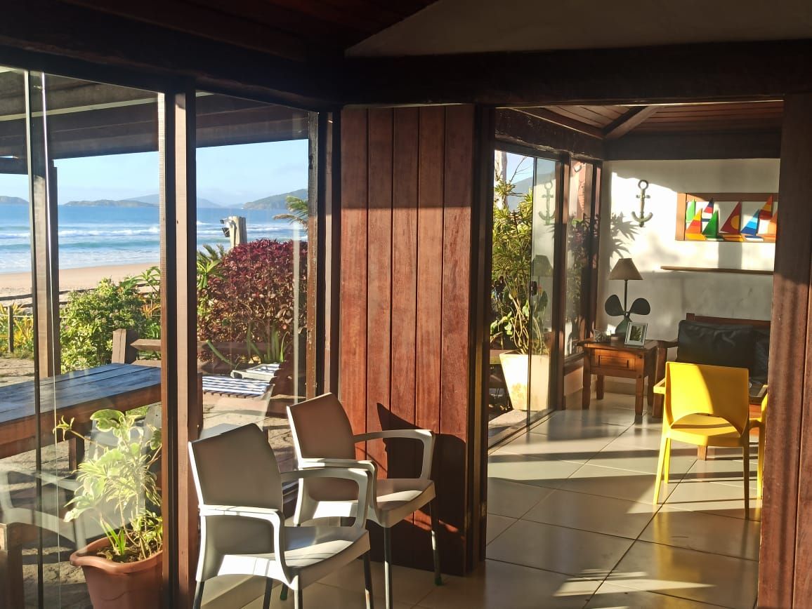 Une pièce avec vue sur l’océan, un mur en bois et un coin repas comprenant des chaises et une table.