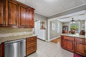 A kitchen with wooden cabinets, a dishwasher, and a granite countertop. - Heritage Home on Miller - Historic Charm & Modern Comfort 3BR (Burley)