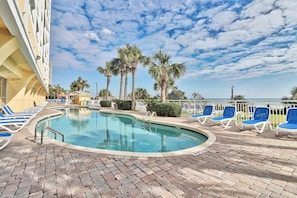 A pool area with lounge chairs and palm trees. - Camelot By The Sea Resort (Myrtle beach)