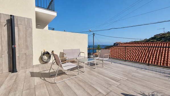 Eine Terrass mit Sofa, Stühlen und einem Tisch.