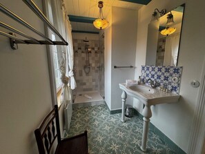 A bathroom with a shower, a sink, a mirror, and patterned floor tiles. - Det Danske Hus - Apartment Starboard (Dunsum)