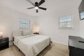 A bedroom with a bed, bedside tables, a ceiling fan, and windows. - Cozy Atlanta Getaway | 3 Bedroom Near Airport (East Point)