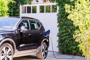 Un SUV noir était garé à l’extérieur, avec un câble de recharge branché à une borne de recharge.