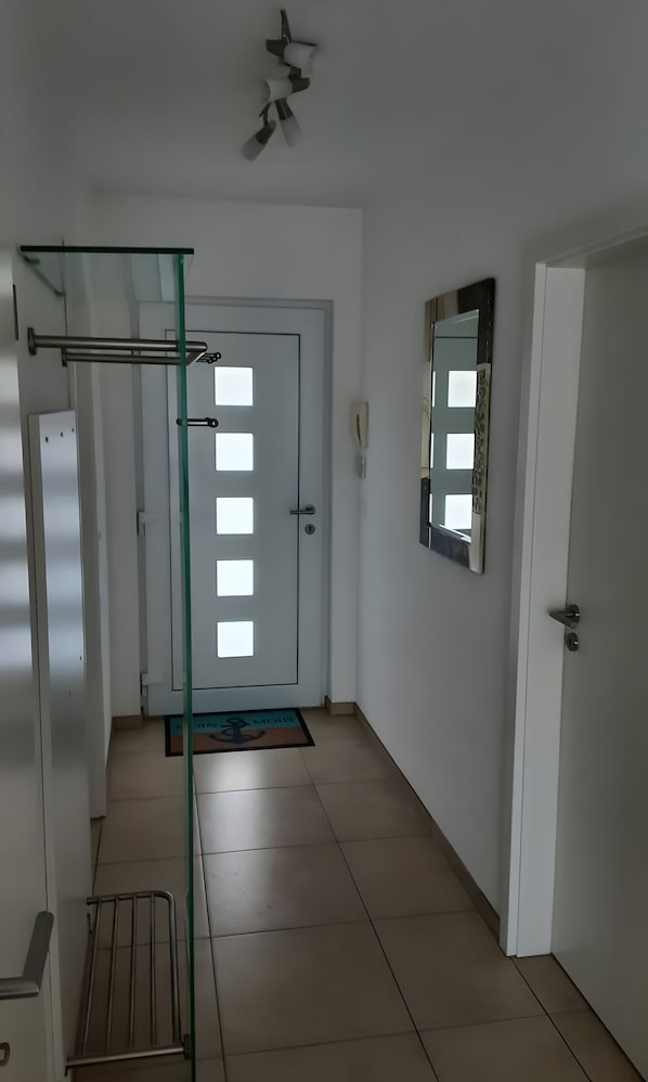 A hallway with a glass door, a mirror, and a ceiling fan.