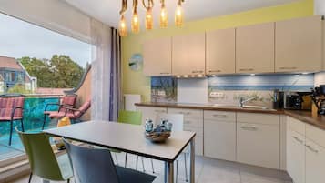 Eine moderne Küche mit Essbereich, ausgestattet mit einem großen Fenster, Blick ins Freie und einer dekorativen Leuchte.
