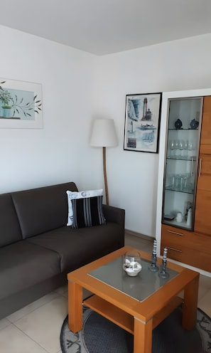 A modern living room with a sofa, a coffee table, a lamp, and a cabinet with glass doors.
