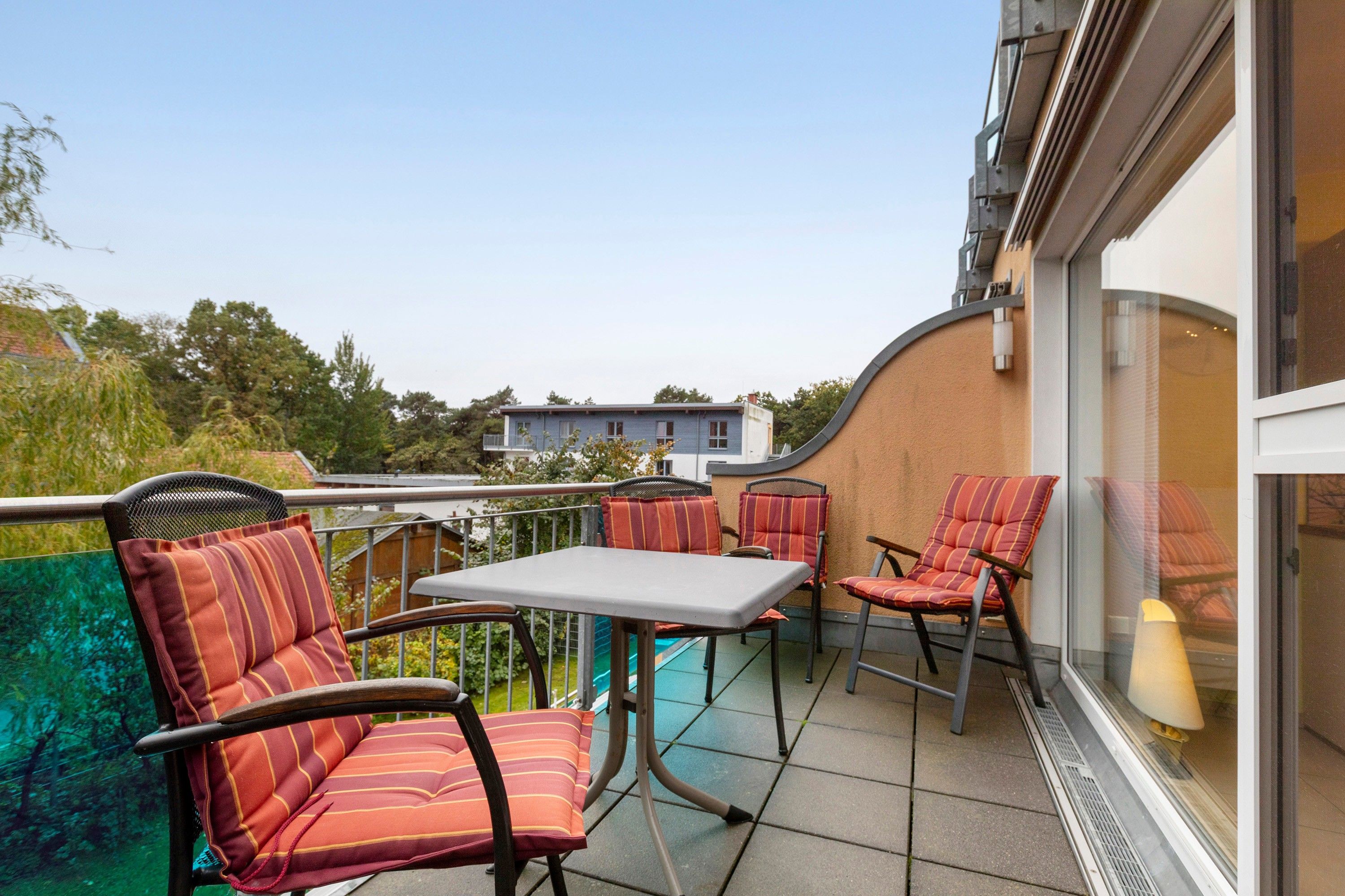 Ein Balkon mit Tisch und Stühlen, Blick auf die Umgebung und ein Gebäude im Hintergrund.