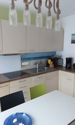 A modern kitchen with a white countertop, stainless steel sink, and a coffee maker.