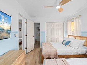 A bedroom with a bed, a desk, a ceiling fan, and a door leading to another room. - Lake Toho Haven | Vintage Boho Style & Park Views (Kissimmee)