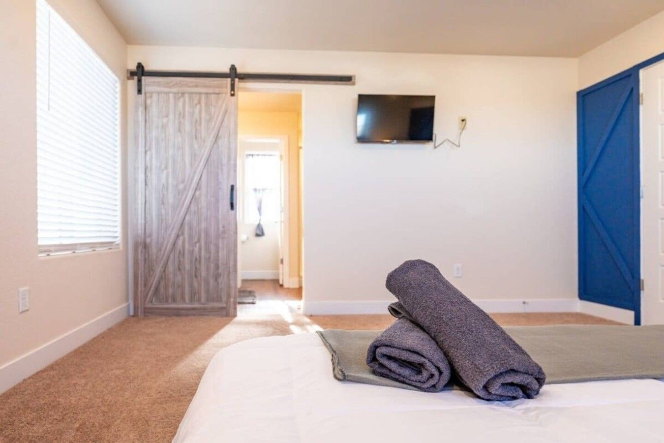 A hotel room with a bed, a television mounted on the wall, and a sliding door.