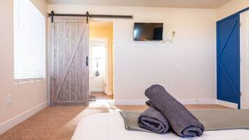 A hotel room with a bed, a television mounted on the wall, and a sliding door.