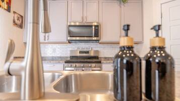 A modern kitchen with stainless steel appliances, a white backsplash, and decorative bottles.