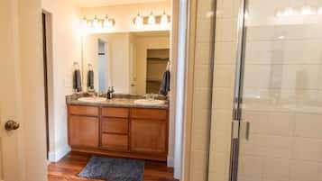 A bathroom with a wooden vanity, a mirror, and a shower area.