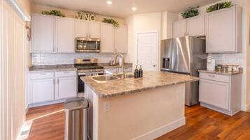 A modern kitchen with white cabinetry, stainless steel appliances, and a granite countertop island.