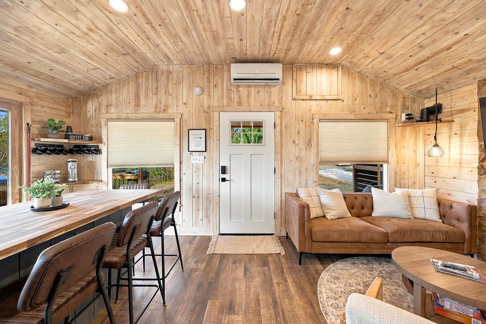 A wooden interior with a bar area, seating, and a door with a view.