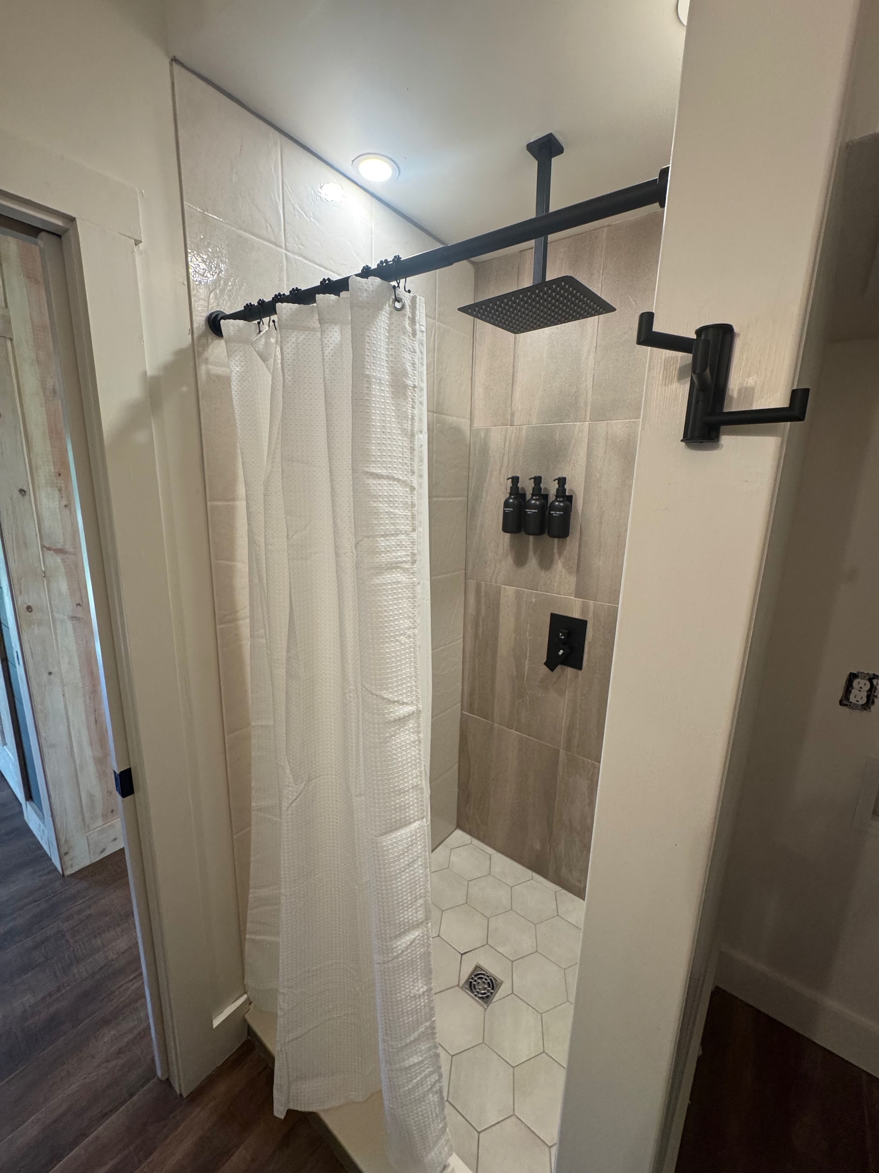 A shower area with a glass door, a showerhead, and a towel rack.