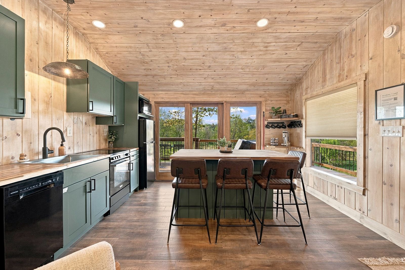 A kitchen with a central island, bar stools, and a view of the outdoors.