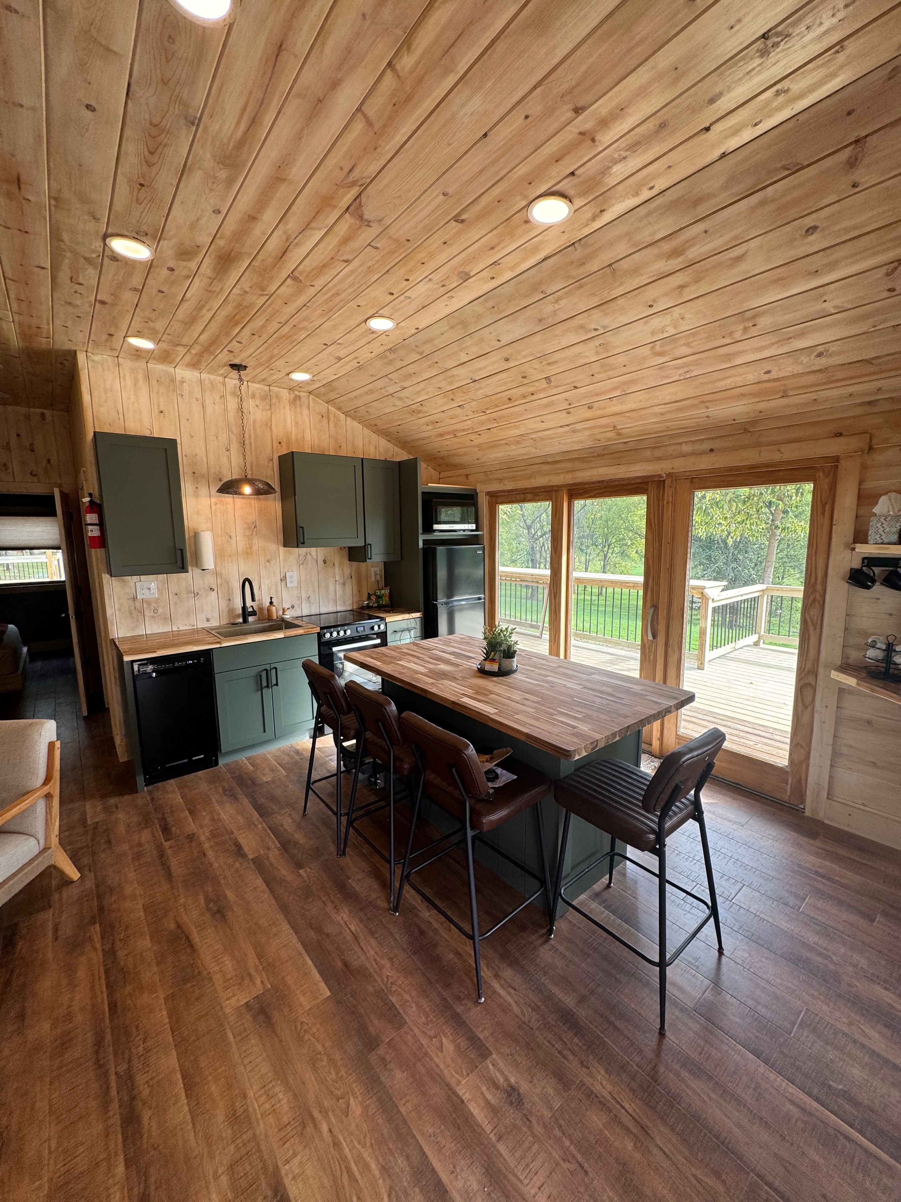 Un intérieur en bois comprenant une cuisine, un coin repas et une vue sur l’extérieur.