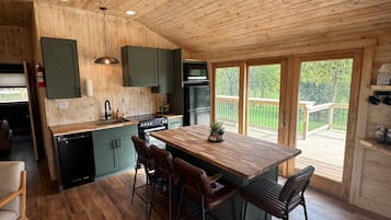 Un intérieur en bois comprenant une cuisine, un coin repas et une vue sur l’extérieur.