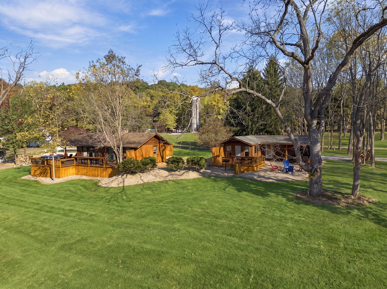 A lodge with two cabins, a covered deck, and a lawn.