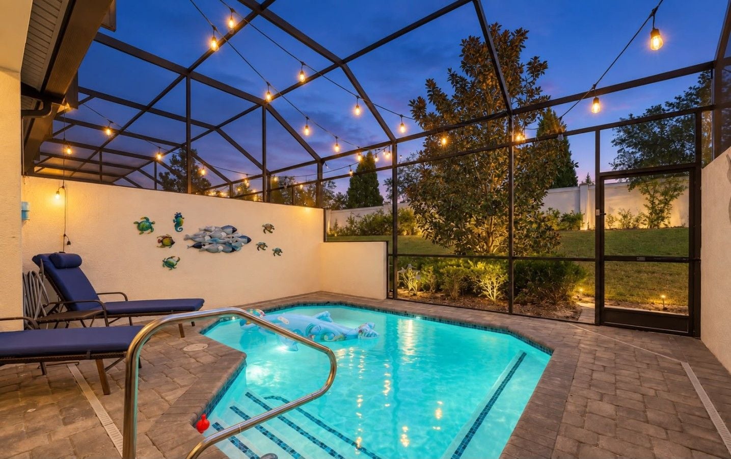 Une piscine dotée d’une enceinte en verre, de chaises longues et d’œuvres d’art décoratives murales.