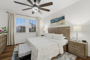A bedroom with a bed, bedside tables, a ceiling fan, a window with curtains, and a painting on the wall. - 4BR Getaway | Private Pool & Family Fun (Davenport)