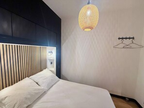 Un dormitorio moderno con cama, lámpara colgante y perchero de pared.
