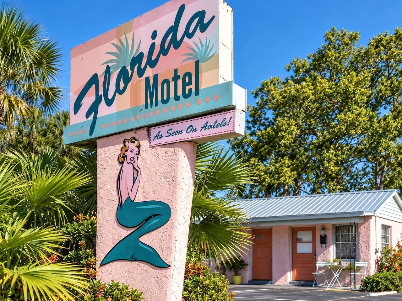 Letrero de motel con ilustración de una sirena y el texto 'Florida Motel, visto en Atlets!'.