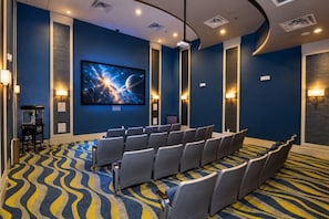 A movie theater with rows of seats, a large screen, and wall-mounted lights. - 4BR Champions Gate Villa | Oasis Club Amenitie’s (Kissimmee)