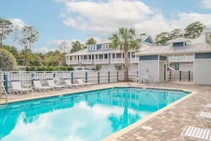 A swimming pool with lounge chairs and a building with a balcony in the background. - 30A Upscale Villa | Coastal Charm & Beach Access (Santa Rosa Beach)