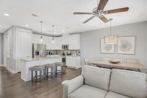 A modern kitchen with white cabinetry, stainless steel appliances, and a central island with bar stools. - 30A Upscale Villa | Coastal Charm & Beach Access (Santa Rosa Beach)