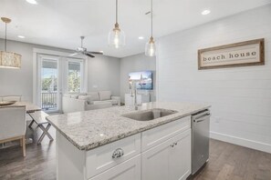 A modern kitchen with a granite countertop, white cabinetry, and a built-in dishwasher. - 30A Upscale Villa | Coastal Charm & Beach Access (Santa Rosa Beach)