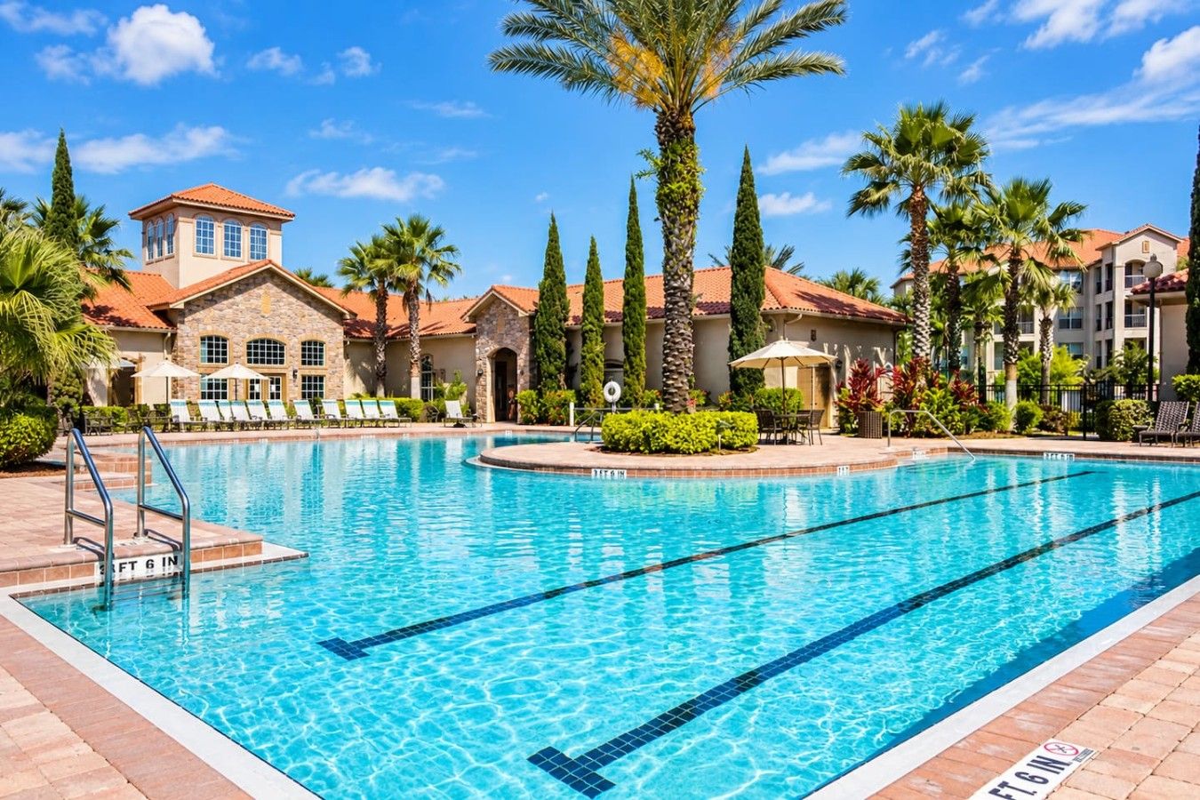 A swimming pool with clear blue water, surrounded by lounge chairs and palm trees.