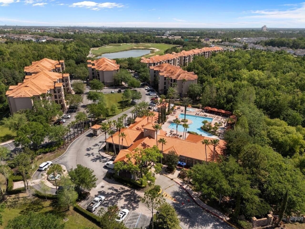 A resort with multiple buildings, a swimming pool, and a parking area.